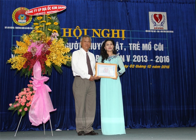  Bà Đặng Thị Kim Oanh nhận bảng tri ân “Tấm lòng vàng” từ Hội người tàn tật, trẻ mồ côi và bệnh nhân nghèo tỉnh Bình Dương do ông Nguyễn Văn Nam trao tặng.
